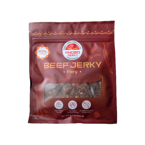 A 2 oz bag of KHOBO Jerky 'Fiery' grassfed tender Vietnamese beef jerky, featuring a dark red packaging design with lots of lemongrass and thai chili